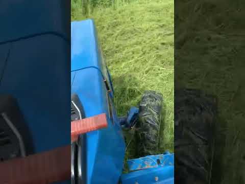Ford 1220 tractor cutting high grass